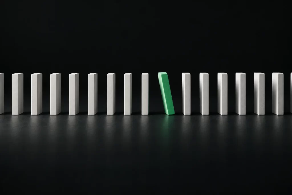 A row of upright tiles with one green tile starting to lean