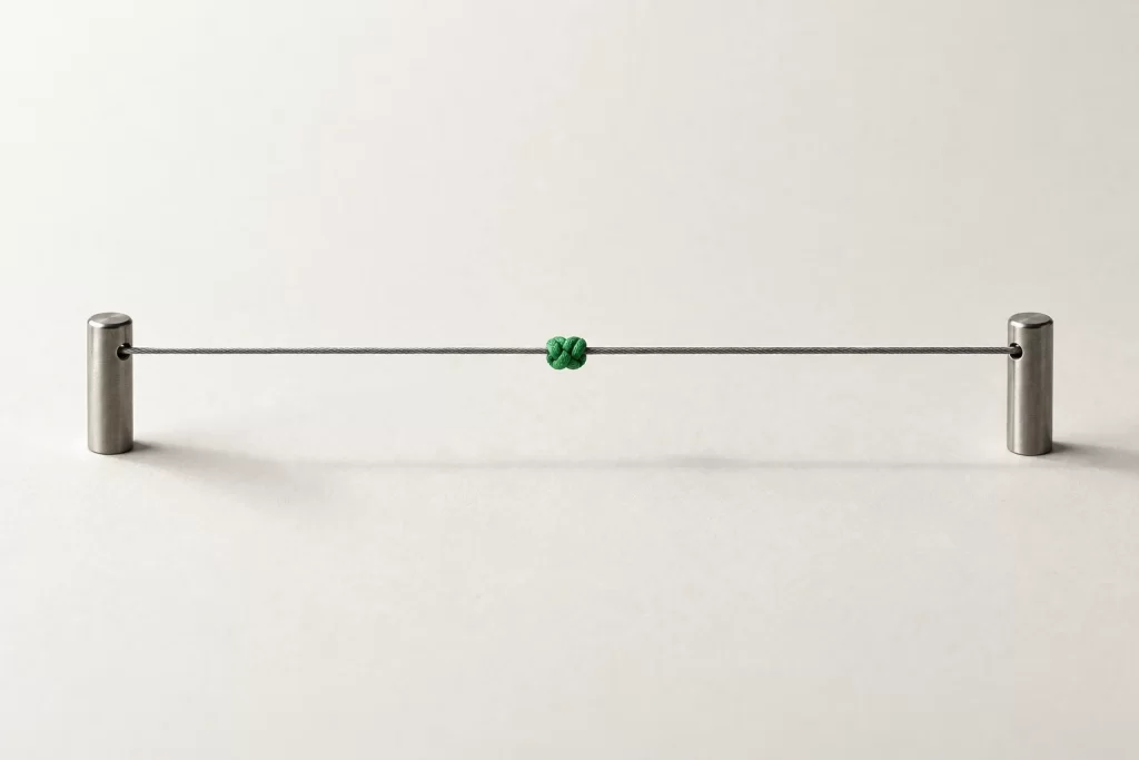 A taut cord between two posts with one green knot
