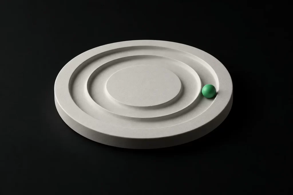A ceramic disc with concentric grooves and a green sphere in the outer ring