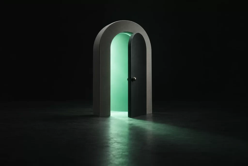 An arched doorway with its door slightly open and green light spilling out